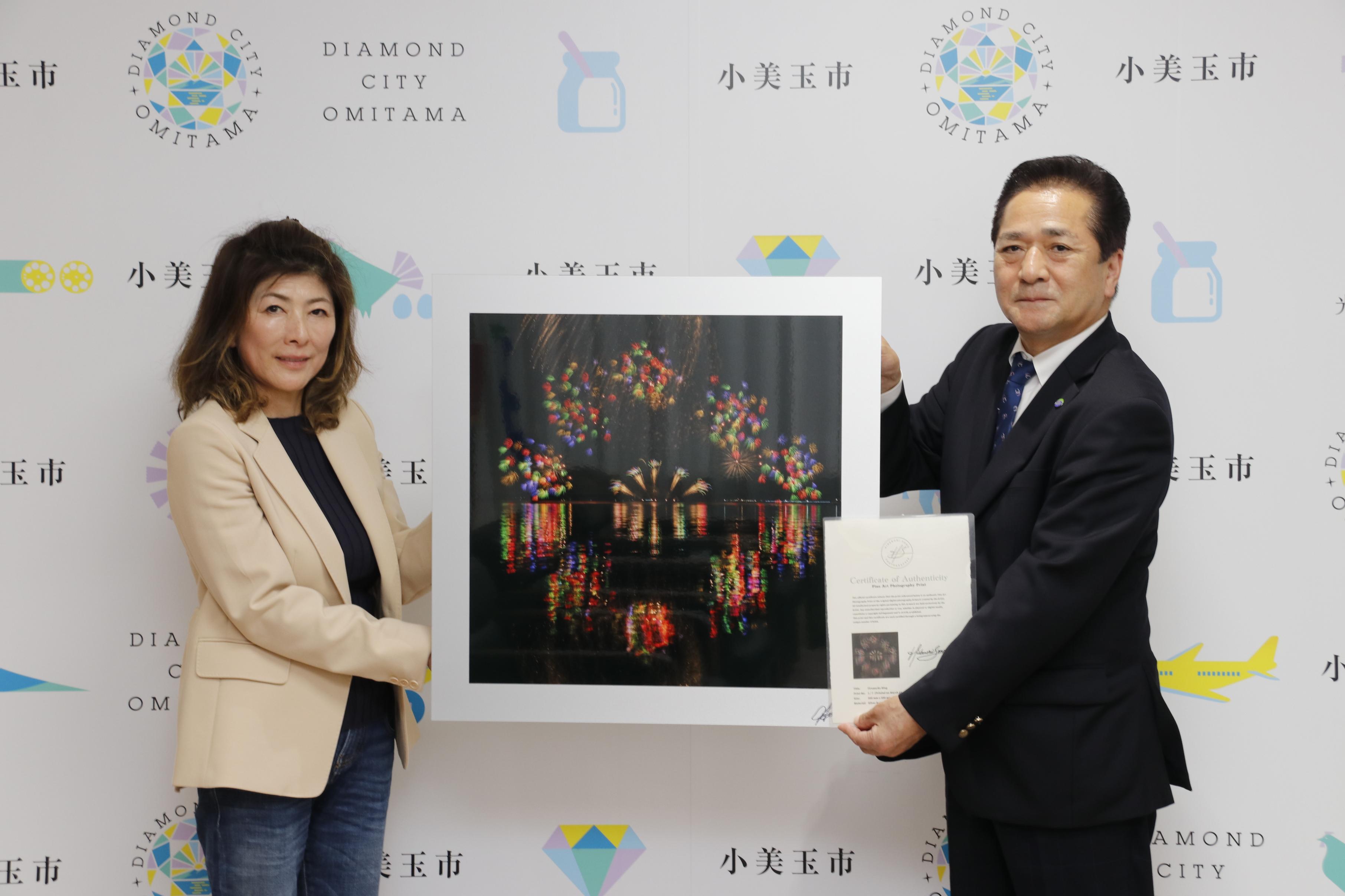 花火大会の写真を持つ市長